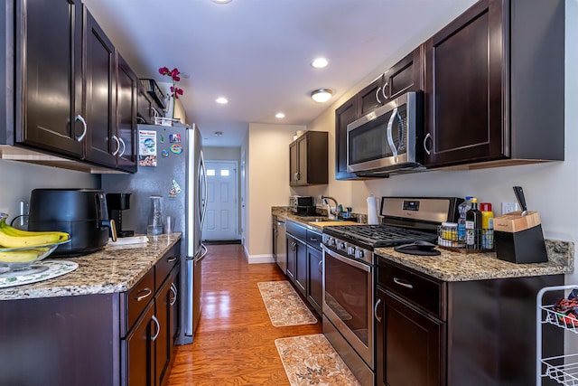 kitchen with recessed lighting, a sink, dark brown cabinetry, appliances with stainless steel finishes, and light wood-type flooring