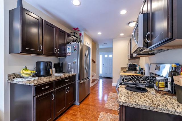 kitchen with recessed lighting, stainless steel appliances, light wood-style floors, baseboards, and dark brown cabinets