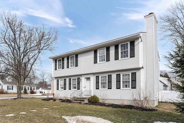 colonial inspired home featuring a front lawn, a chimney, and fence