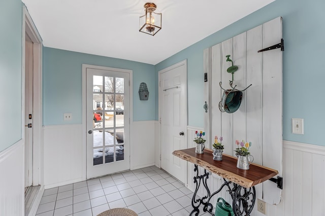 doorway to outside featuring light tile patterned floors and wainscoting