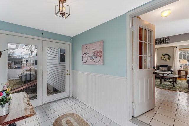 doorway to outside featuring a wainscoted wall and light tile patterned flooring