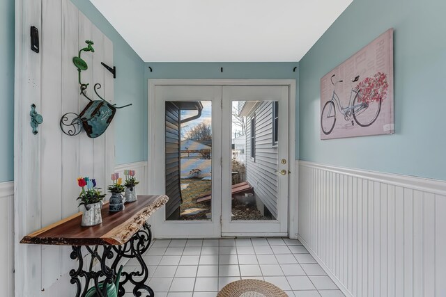 doorway with light tile patterned floors and wainscoting