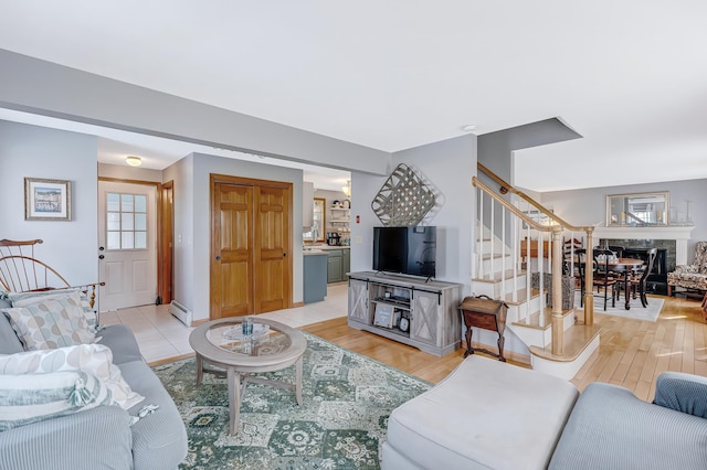 living area featuring stairs, light wood-style flooring, and a baseboard radiator