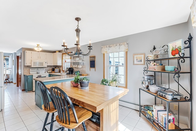 dining room with light tile patterned floors, baseboard heating, and a notable chandelier