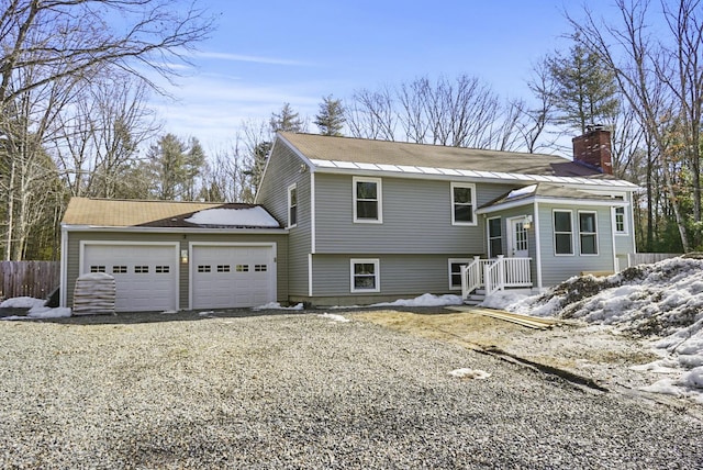 view of front of house with a garage, a chimney, driveway, and fence