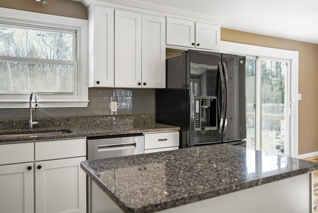 kitchen featuring a wealth of natural light, black fridge, tasteful backsplash, and a sink