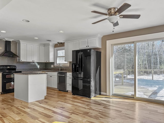 kitchen featuring white cabinetry, black appliances, light wood-style flooring, and wall chimney range hood