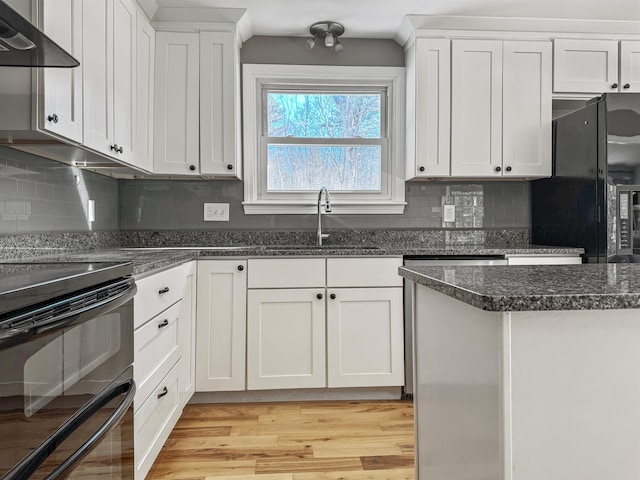 kitchen with light wood-style flooring, a sink, extractor fan, black appliances, and white cabinets