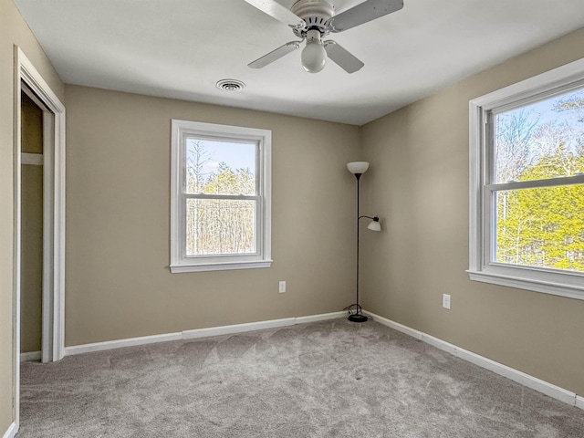 carpeted empty room with visible vents, ceiling fan, and baseboards