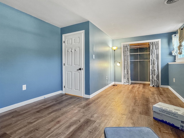 spare room featuring visible vents, baseboards, and wood finished floors