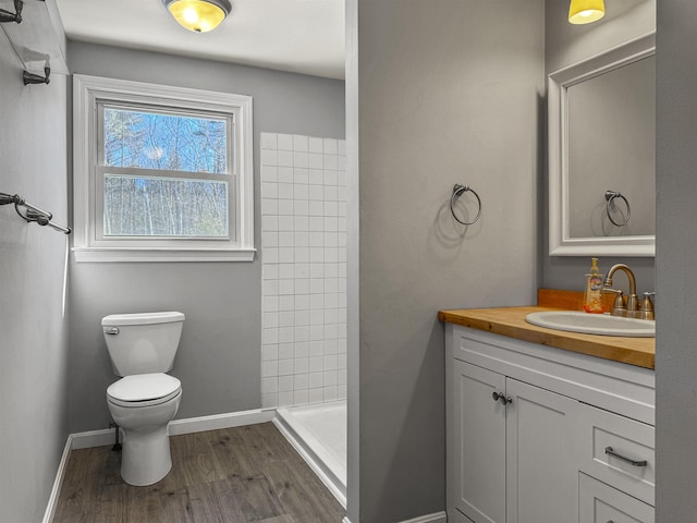 bathroom featuring vanity, wood finished floors, baseboards, a shower stall, and toilet