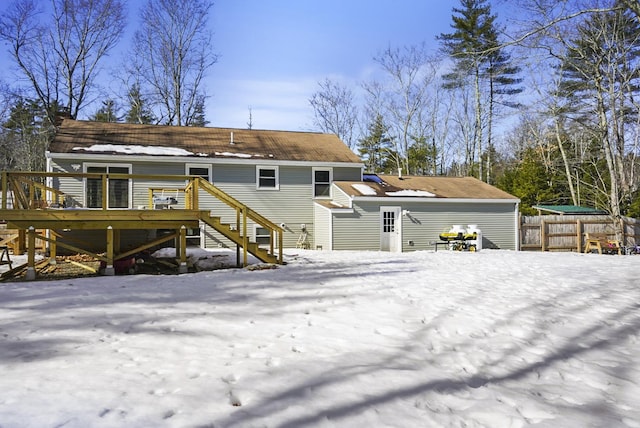 snow covered back of property featuring stairs, a deck, and fence