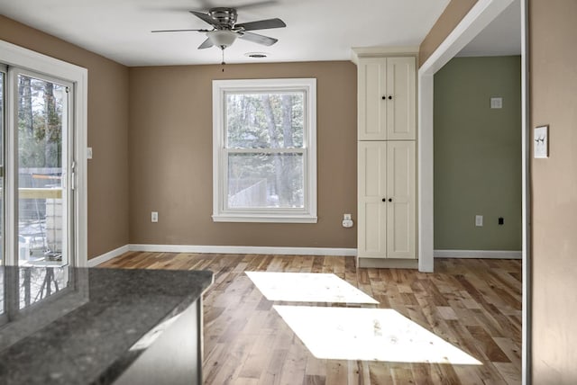 unfurnished dining area with light wood-style flooring, baseboards, and ceiling fan