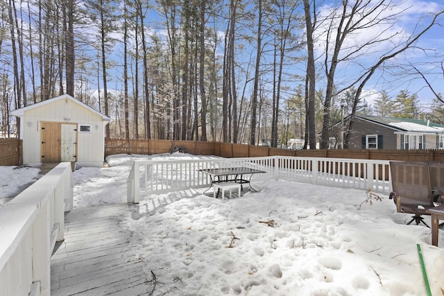 snowy yard featuring an outbuilding, a storage unit, and a fenced backyard