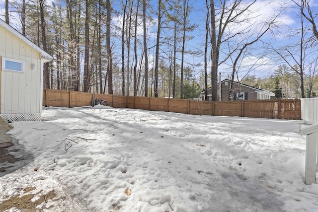 snowy yard featuring a fenced backyard