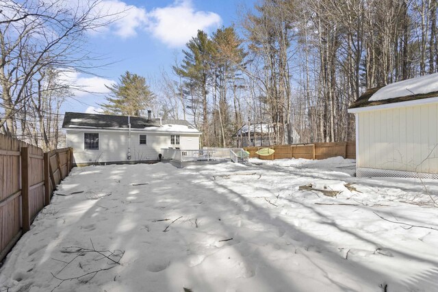 yard layered in snow featuring a deck and a fenced backyard