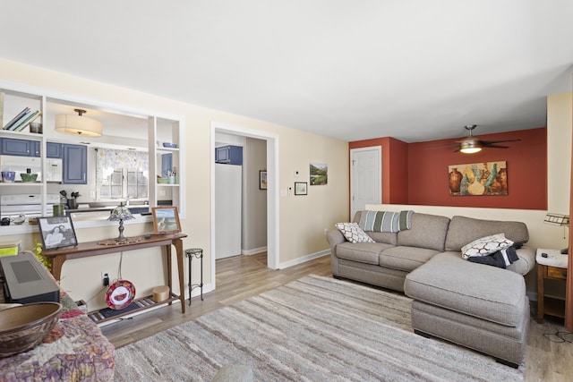 living area featuring baseboards, wood finished floors, and a ceiling fan