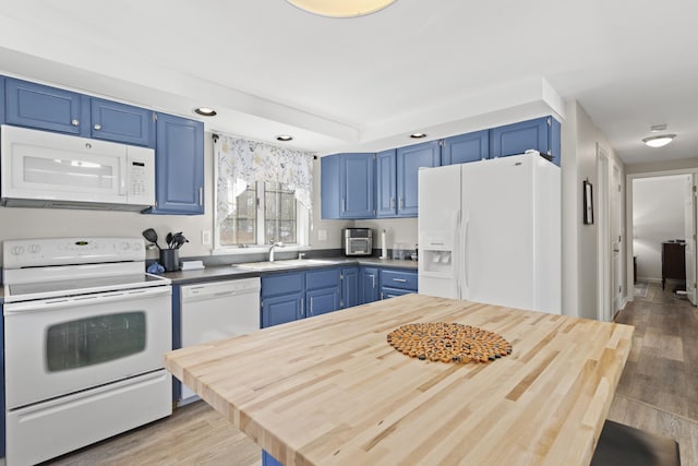 kitchen featuring light wood finished floors, blue cabinetry, wooden counters, white appliances, and a sink