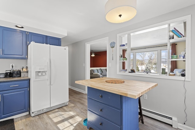 kitchen with a baseboard radiator, blue cabinetry, light wood-style floors, white fridge with ice dispenser, and butcher block counters