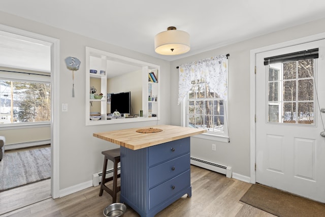 kitchen with a kitchen breakfast bar, blue cabinetry, baseboard heating, and wooden counters