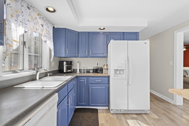 kitchen with a sink, blue cabinetry, white appliances, light wood finished floors, and baseboards