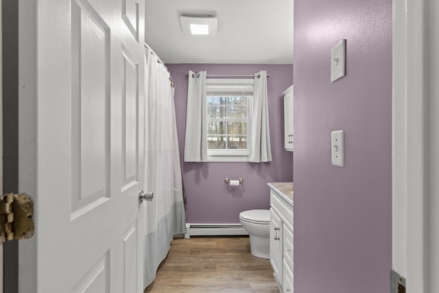 full bathroom featuring toilet, a baseboard heating unit, wood finished floors, a shower with shower curtain, and vanity