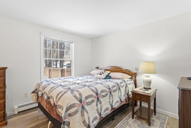 bedroom featuring light wood-type flooring, baseboards, and a baseboard radiator