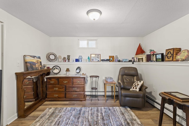 living area featuring a textured ceiling, baseboard heating, and wood finished floors