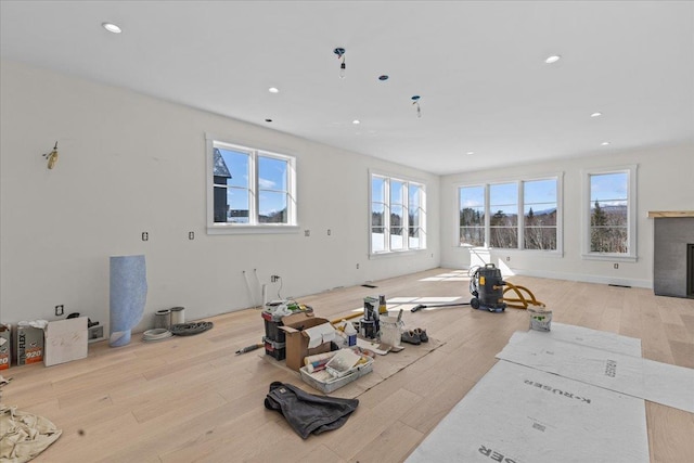 exercise area featuring a glass covered fireplace, recessed lighting, and wood finished floors