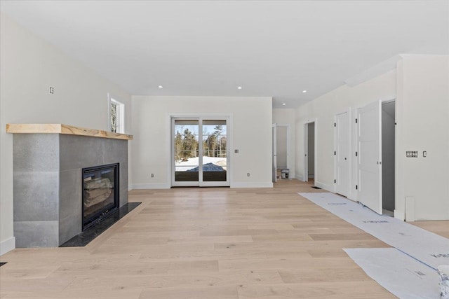 unfurnished living room featuring light wood finished floors, a fireplace with flush hearth, recessed lighting, and baseboards