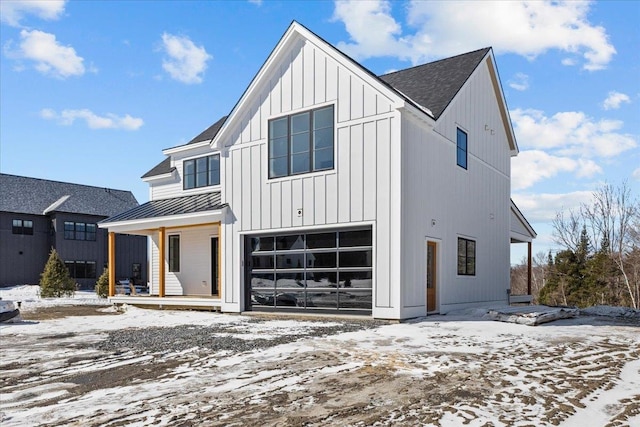 modern farmhouse style home featuring a standing seam roof, a porch, a garage, board and batten siding, and metal roof