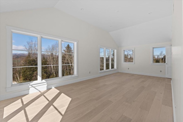 interior space featuring baseboards, light wood finished floors, and vaulted ceiling