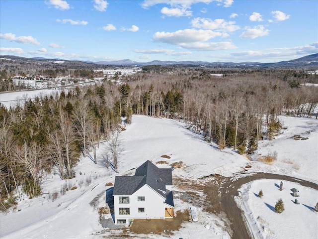 snowy aerial view featuring a mountain view and a forest view