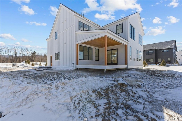 snow covered rear of property featuring board and batten siding