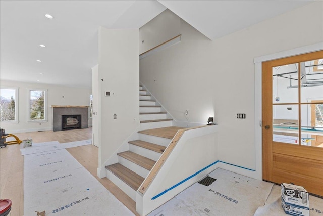 foyer entrance featuring recessed lighting, baseboards, a fireplace, and stairs