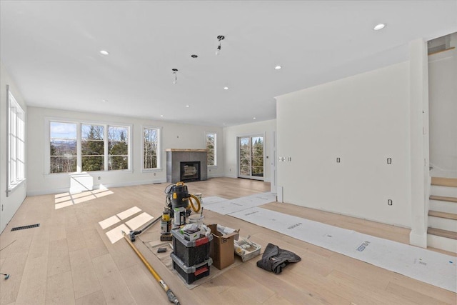 unfurnished living room with a wealth of natural light, visible vents, and light wood-style flooring