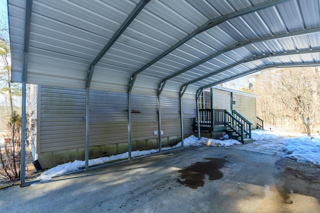 snow covered garage with a carport and driveway