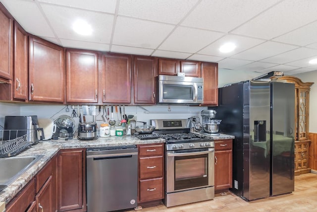 kitchen featuring light wood finished floors, appliances with stainless steel finishes, and light stone countertops