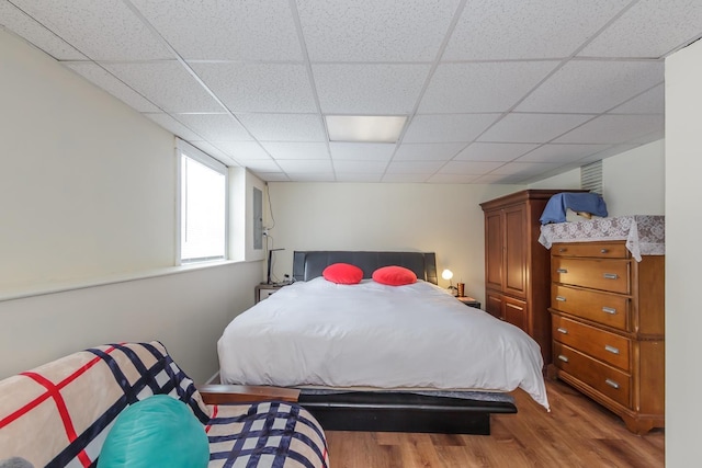 bedroom featuring a drop ceiling and wood finished floors