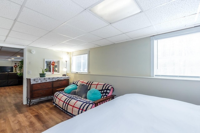 bedroom with a drop ceiling and dark wood finished floors