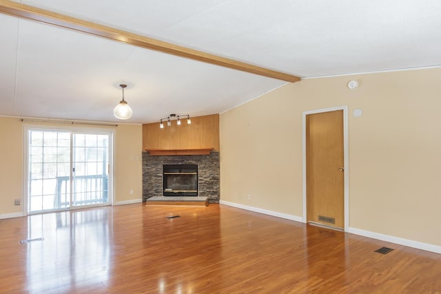 unfurnished living room featuring baseboards, visible vents, lofted ceiling with beams, a stone fireplace, and light wood-type flooring