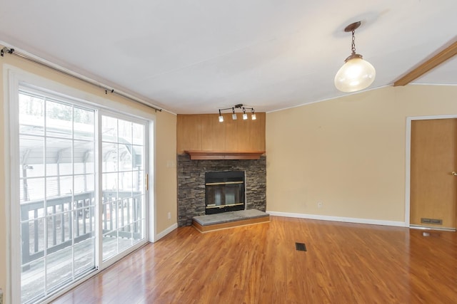 unfurnished living room featuring baseboards, light wood-style floors, a stone fireplace, and vaulted ceiling with beams