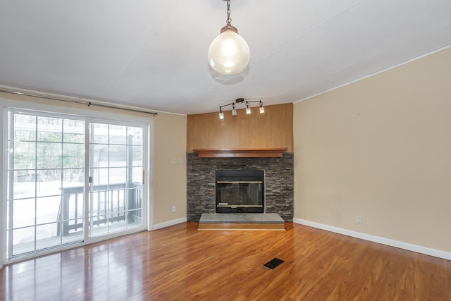 unfurnished living room with track lighting, a fireplace, baseboards, and wood finished floors