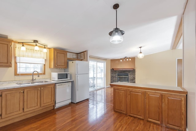 kitchen with white appliances, plenty of natural light, wood finished floors, and a sink