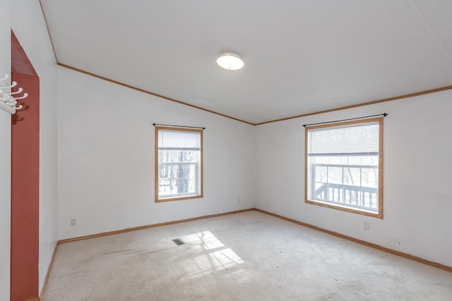 empty room featuring baseboards, carpet, crown molding, and lofted ceiling