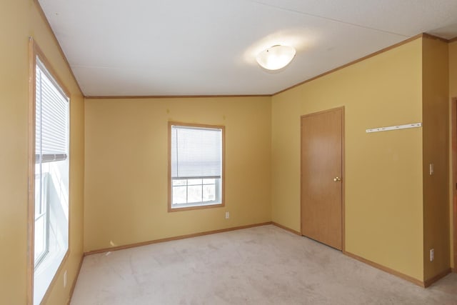 unfurnished room featuring light colored carpet, crown molding, and baseboards