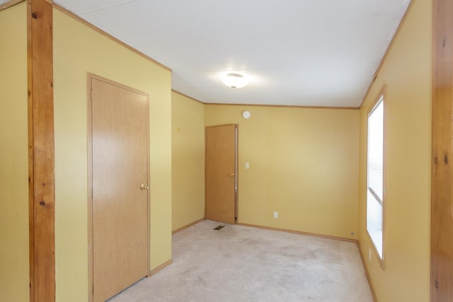 unfurnished room featuring crown molding, light colored carpet, baseboards, and visible vents