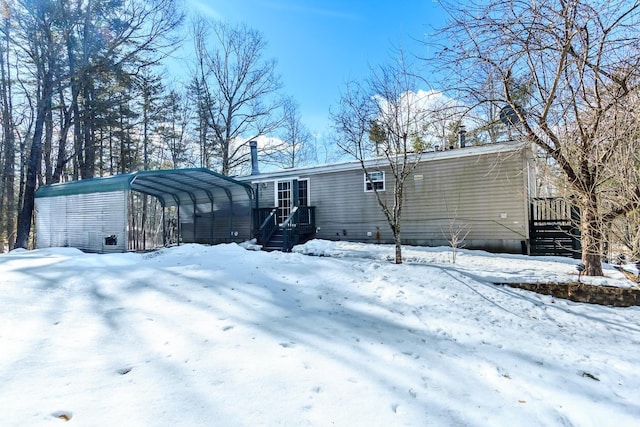 snow covered back of property with a carport