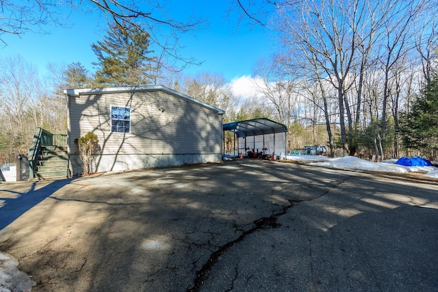 view of side of property with stairs, a carport, and driveway