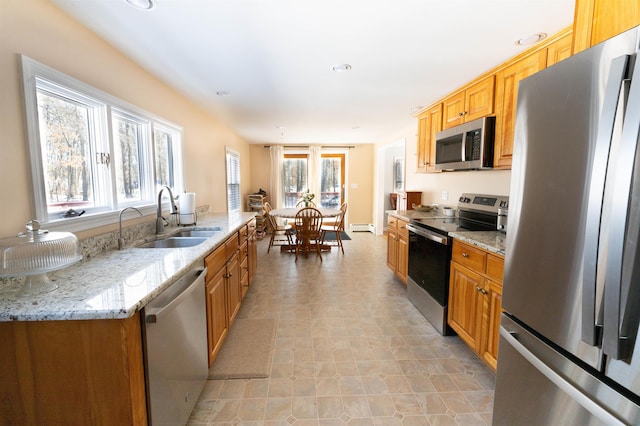 kitchen featuring baseboard heating, a healthy amount of sunlight, stainless steel appliances, and a sink